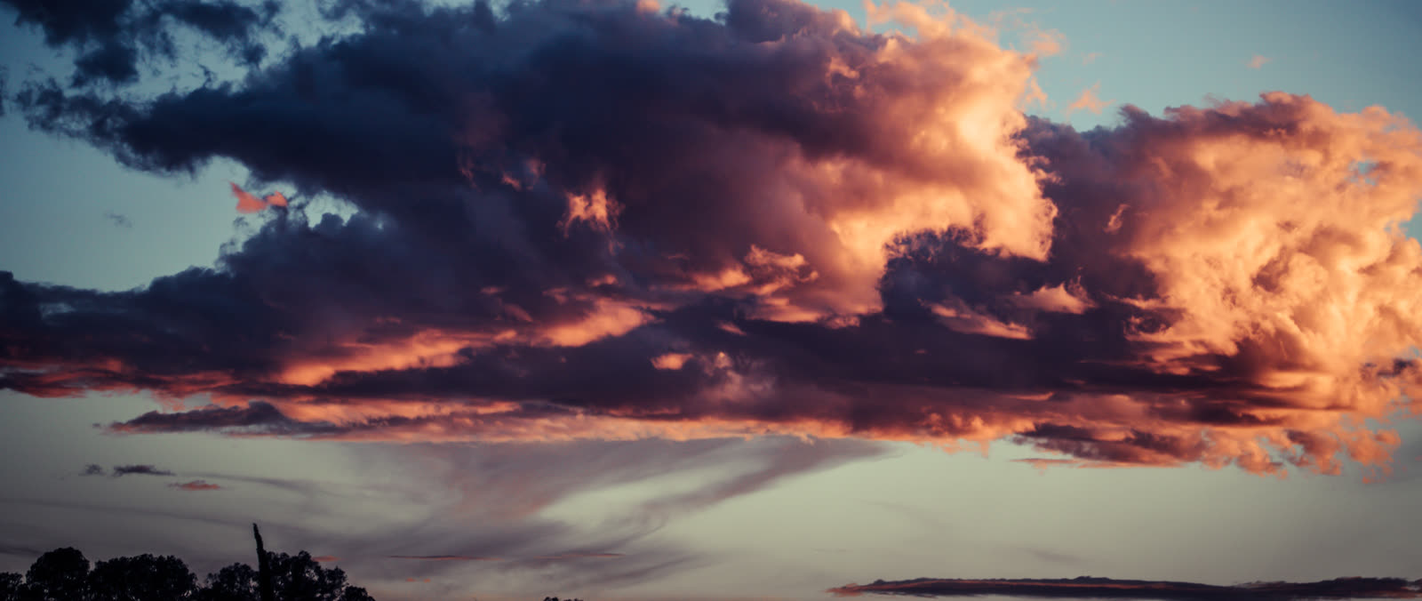 Wide atmospheric cloud band with dark navy depth and restrained gold edge light.